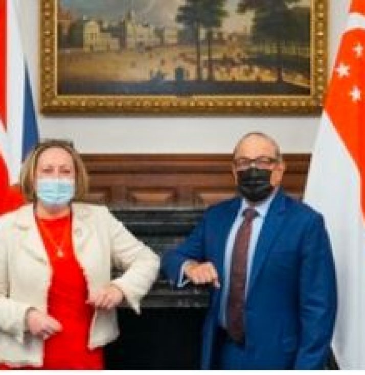 United Kingdom and Singapore flags with country representatives standing in front of them for a new trade deal